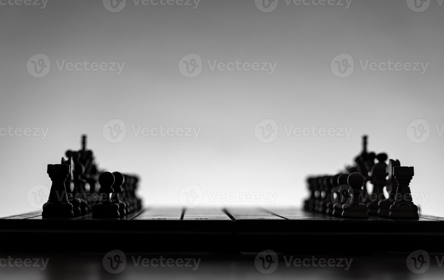 Schachbrett mit Schachfiguren Silhouetten auf weißem Hintergrund. konzept von geschäftsideen, wettbewerbs- und strategieideen. klassisches Kunstfoto in Schwarz-Weiß. alle Figur bereit für den Kampf, vor dem Öffnen foto