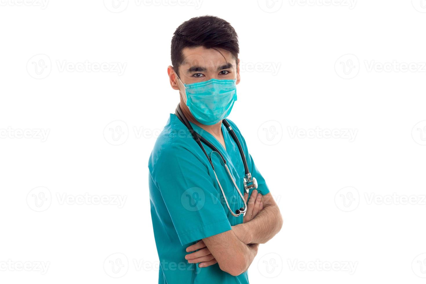 ein junger arzt mit stethoskop und der maske im gesicht schaut in die kamera foto