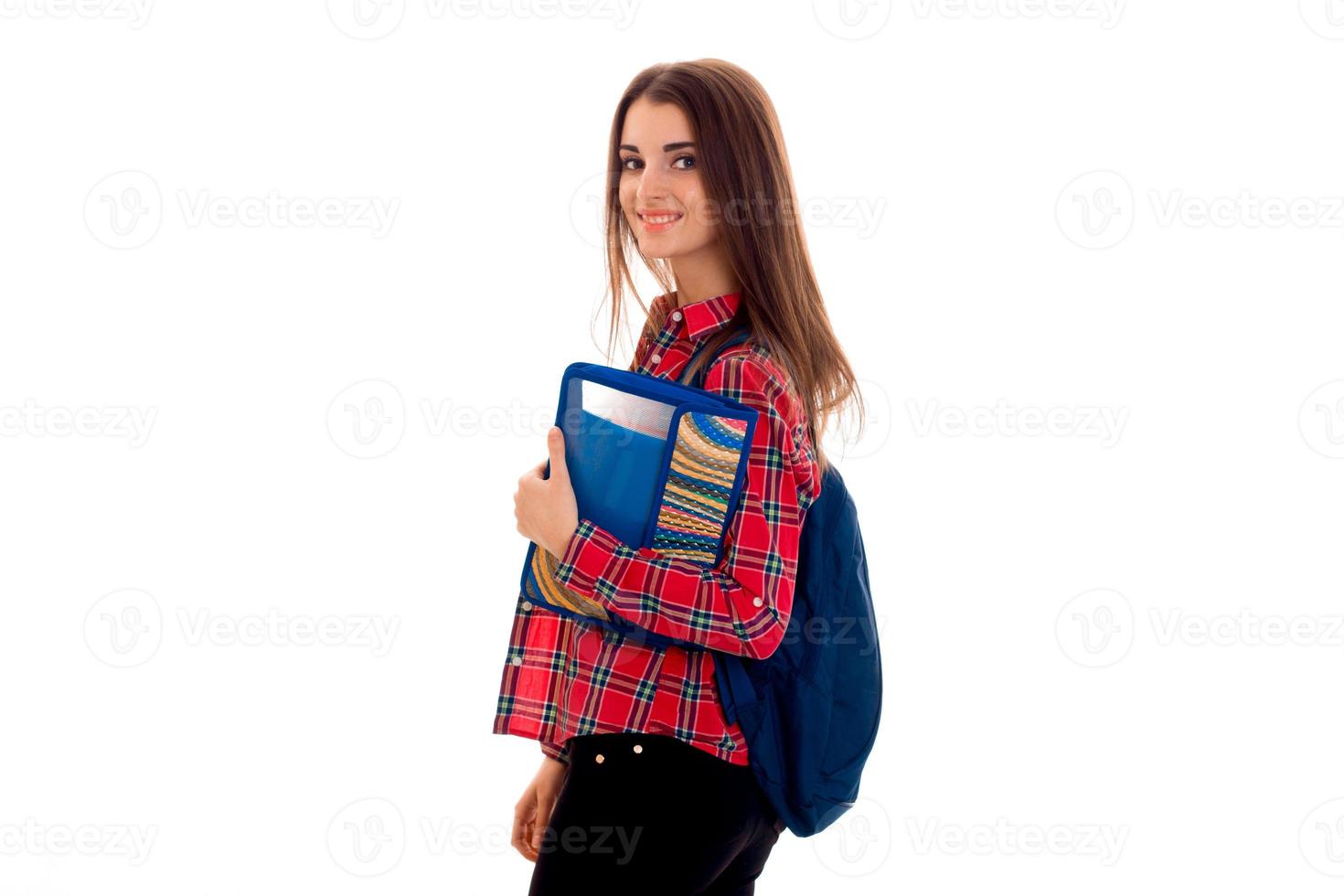 Fröhliche junge Studentin mit Rucksack und Ordner für Notizbücher, die in die Kamera schaut und isoliert auf weißem Hintergrund lächelt. Konzept der Studentenjahre. Studienkonzept. foto