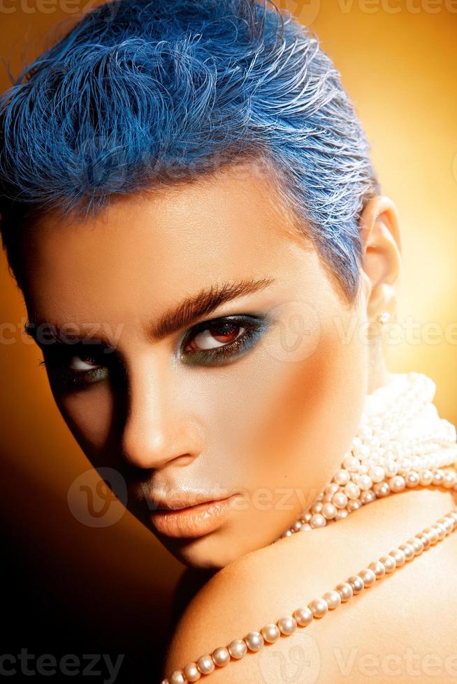 vertikales Foto einer sexy jungen Frau mit blauen Haaren und grünem Make-up