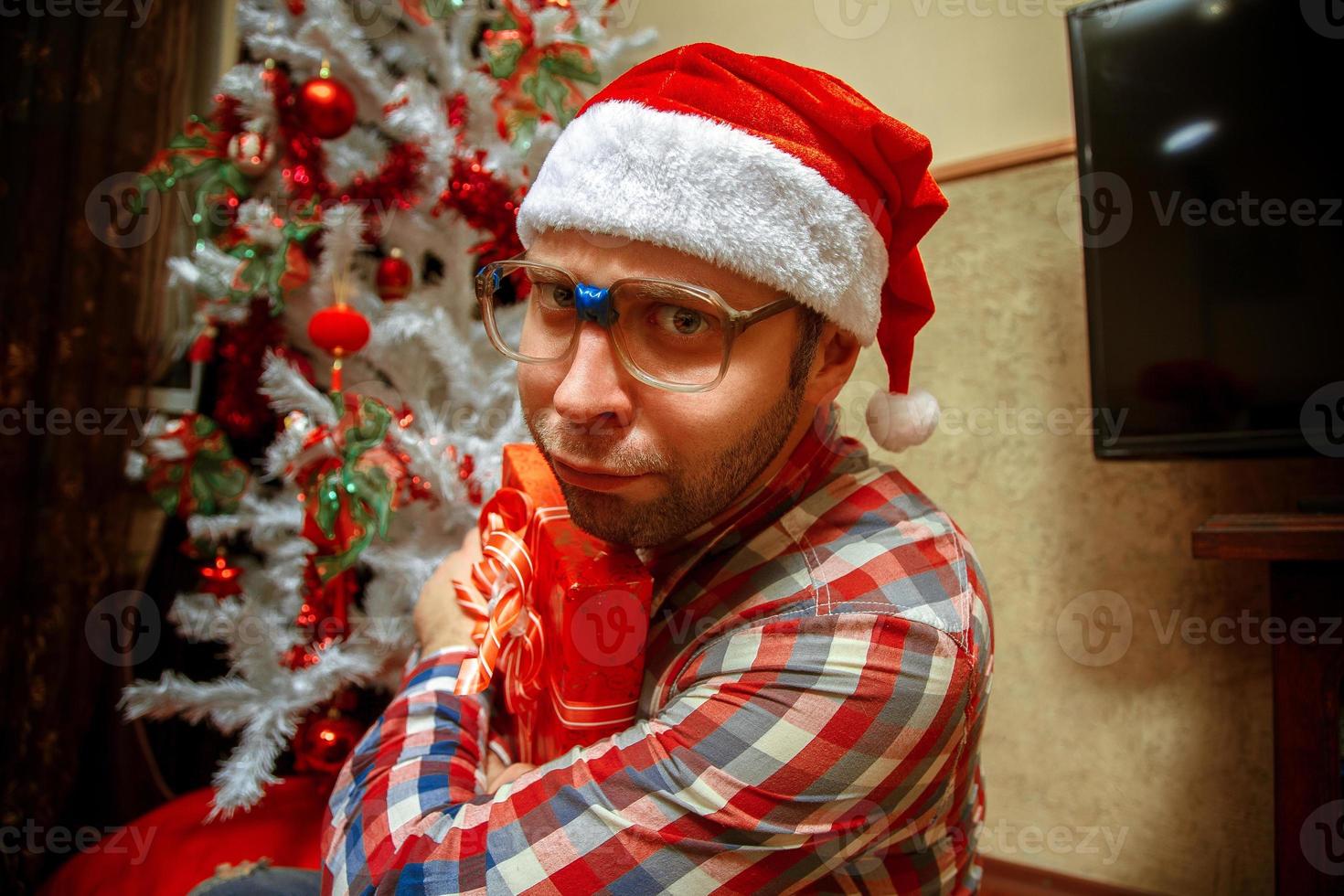 Seriöser Nerd mit Weihnachtsmütze bekommt ein Weihnachtsgeschenk foto