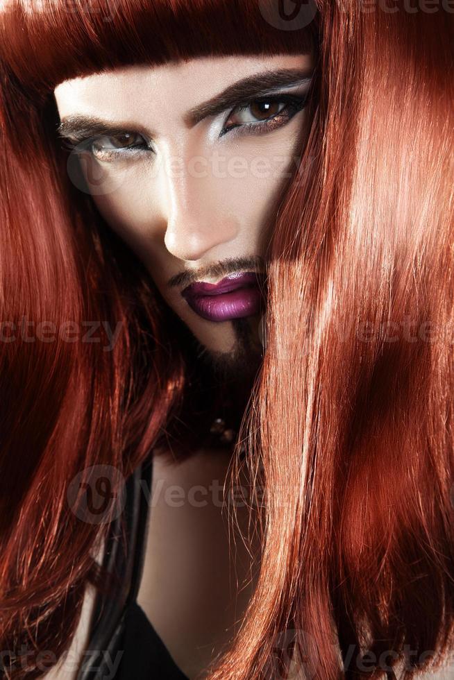 Vertikales Porträt eines schönen Rothaarmannes mit magentafarbenem Make-up foto