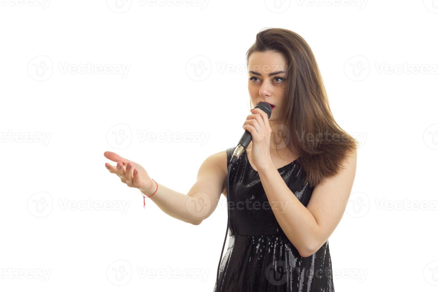 hübsches junges mädchen im schwarzen kleid, das karaoke singt foto