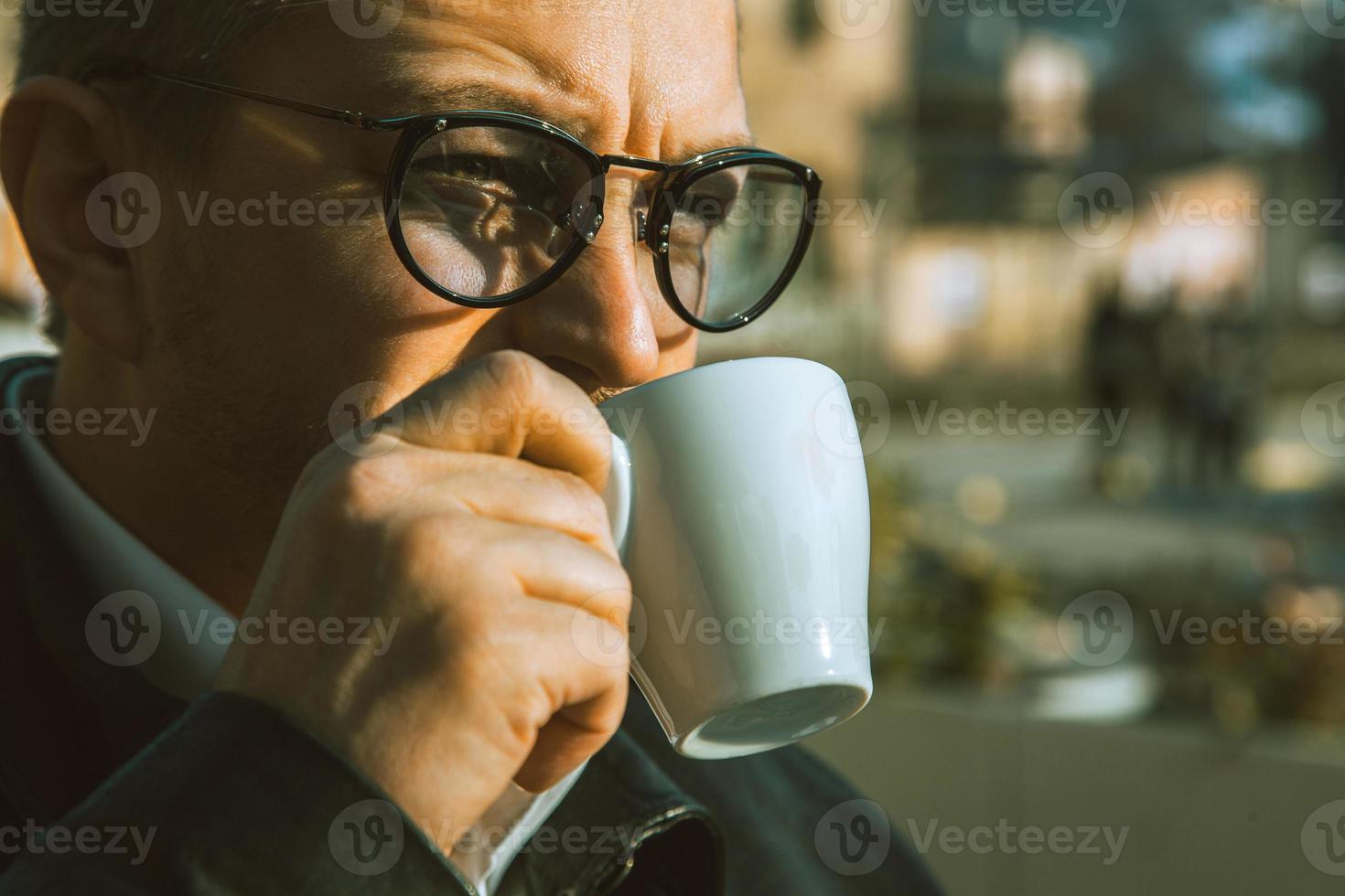 Schließen Sie herauf Porträt des erwachsenen Mannes, der draußen Kaffee trinkt foto