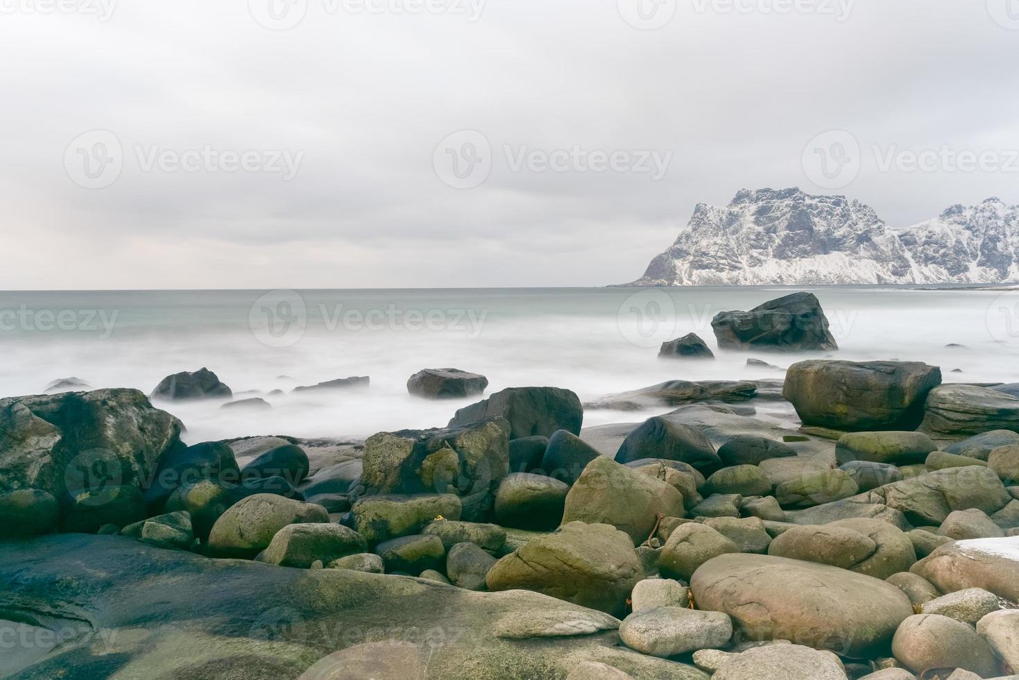 Wellen, die im Winter über den Strand von Utakleiv, Lofoten, Norwegen fließen. foto