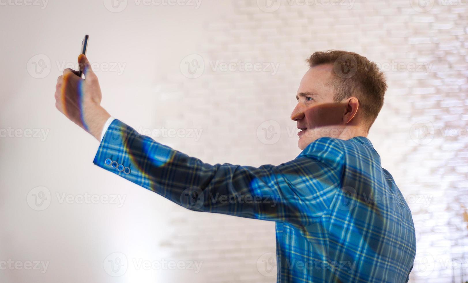 stilvoller geschäftsmann, der blauen anzug trägt und selfie auf dem handy macht foto