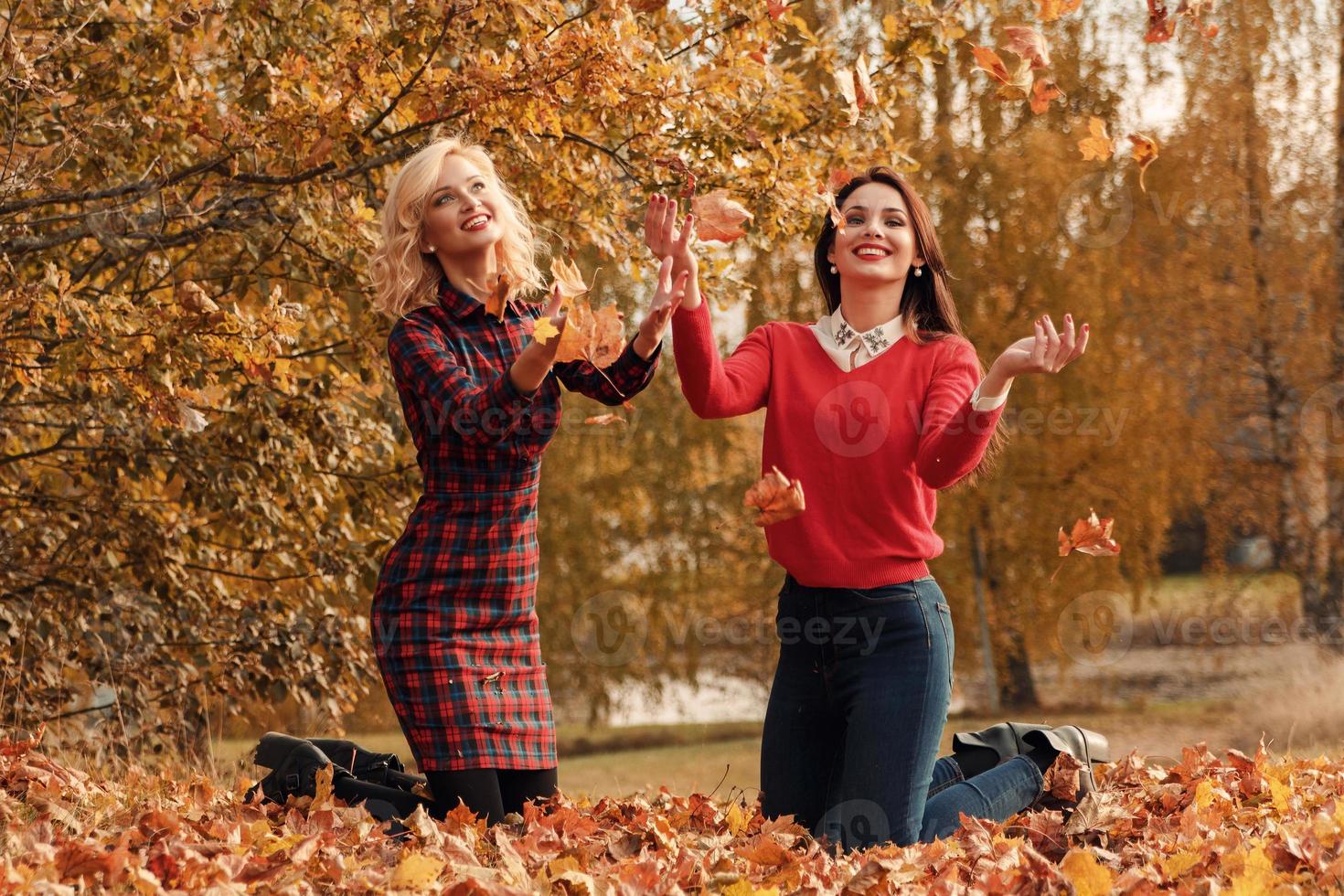 Zwei schöne Freundinnen, die sich im Herbstpark amüsieren foto
