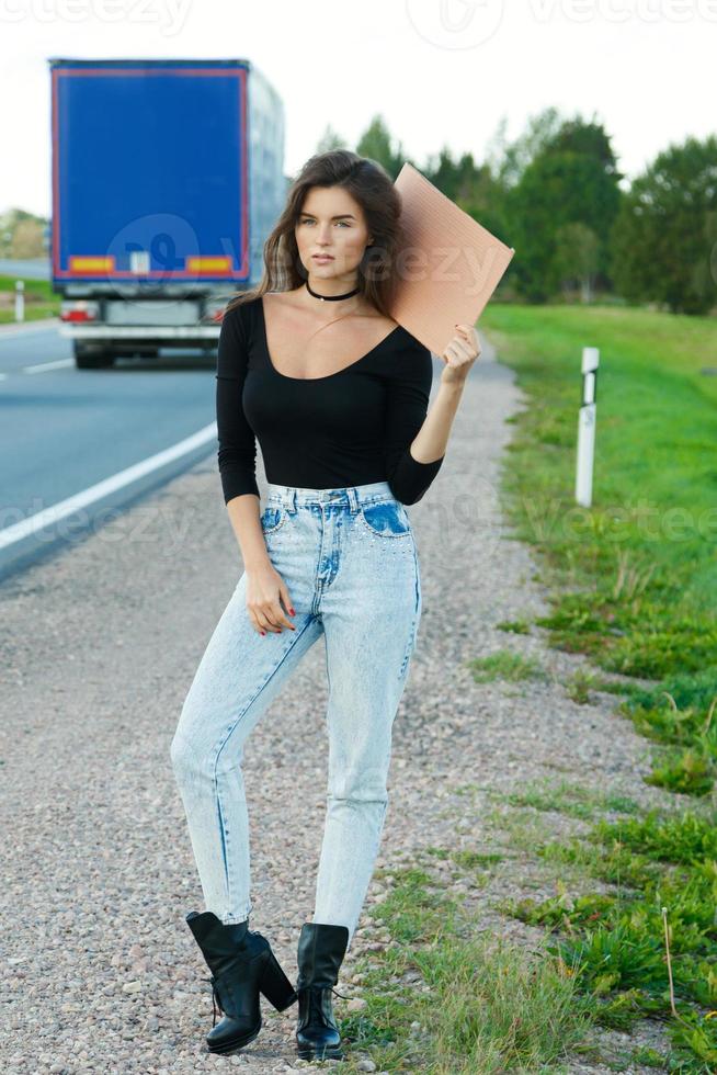 Tramper auf der Straße hält ein leeres Pappschild foto