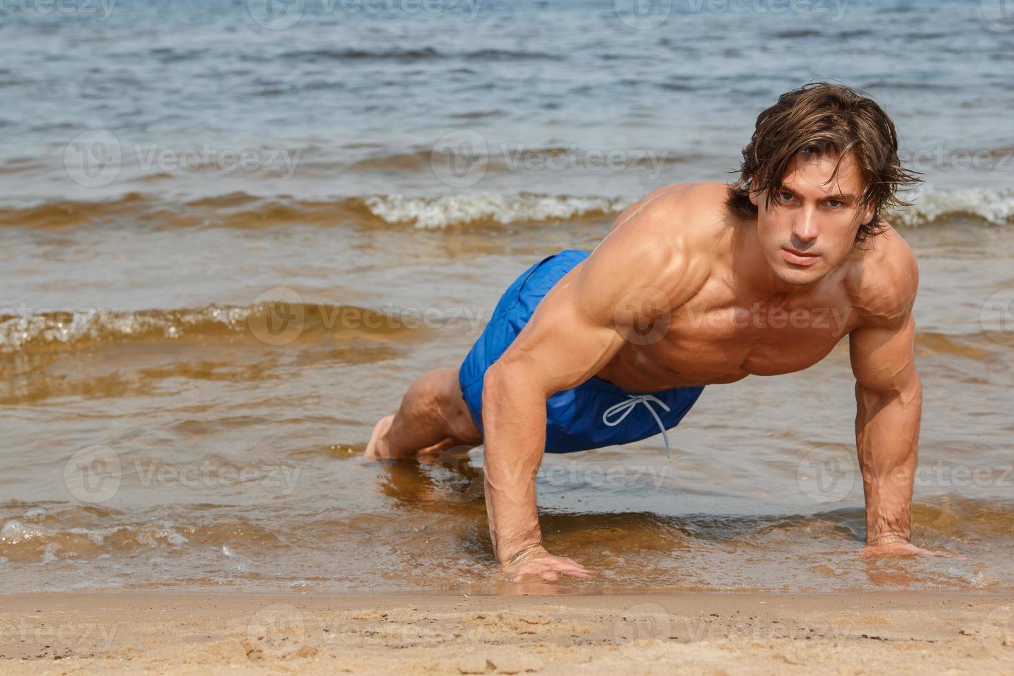 muskulöser Mann während seines Trainings am Strand foto