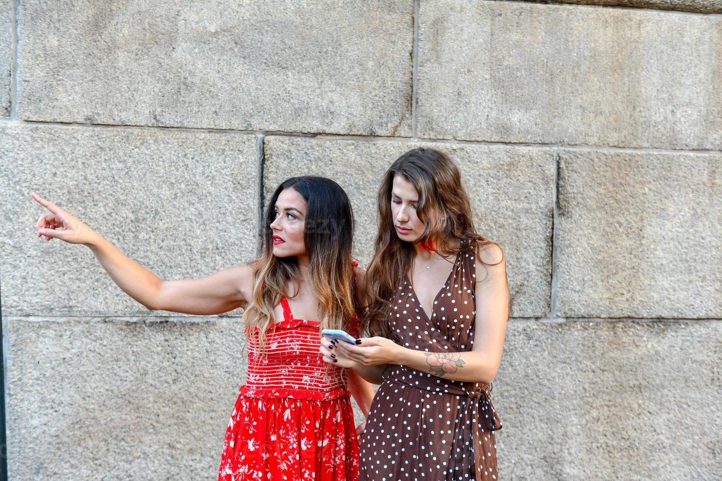 Zwei verlorene Mädchen, die mit einem Mobiltelefon interagieren, um Wegbeschreibungen in New York City zu erhalten foto