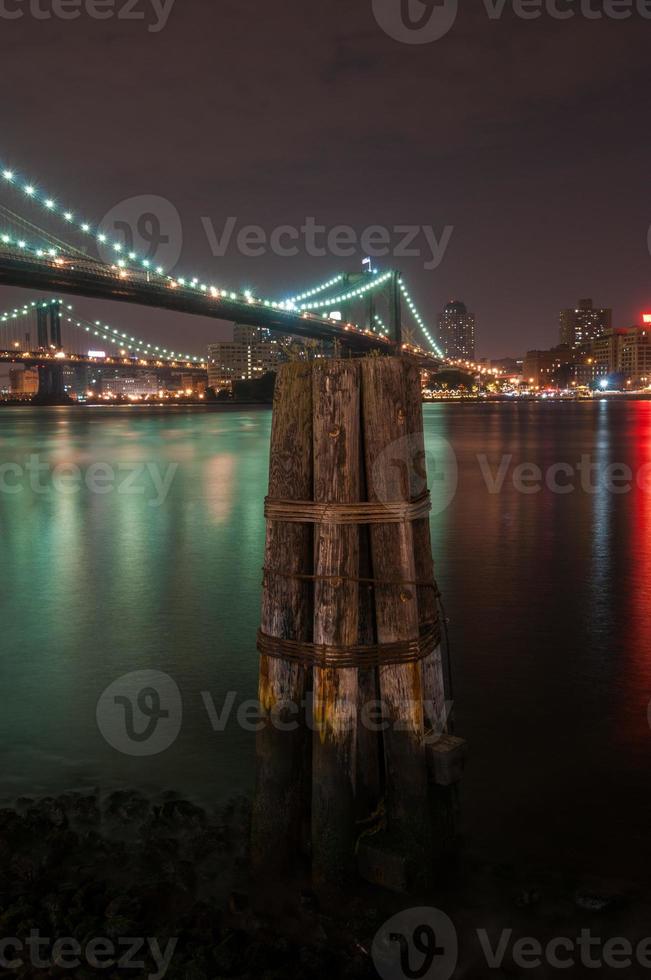 Brooklyn Bridge Nahaufnahme über East River in der Nacht in New York City Manhattan mit Lichtern und Reflexionen. foto