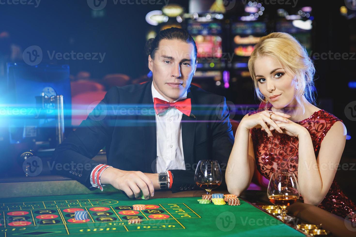 Schönes und reiches Paar, das im Casino Roulette spielt foto