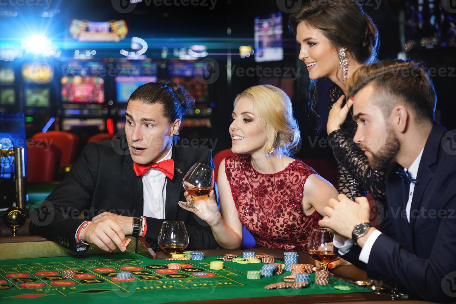 Junge und reiche Leute, die im Casino Roulette spielen foto