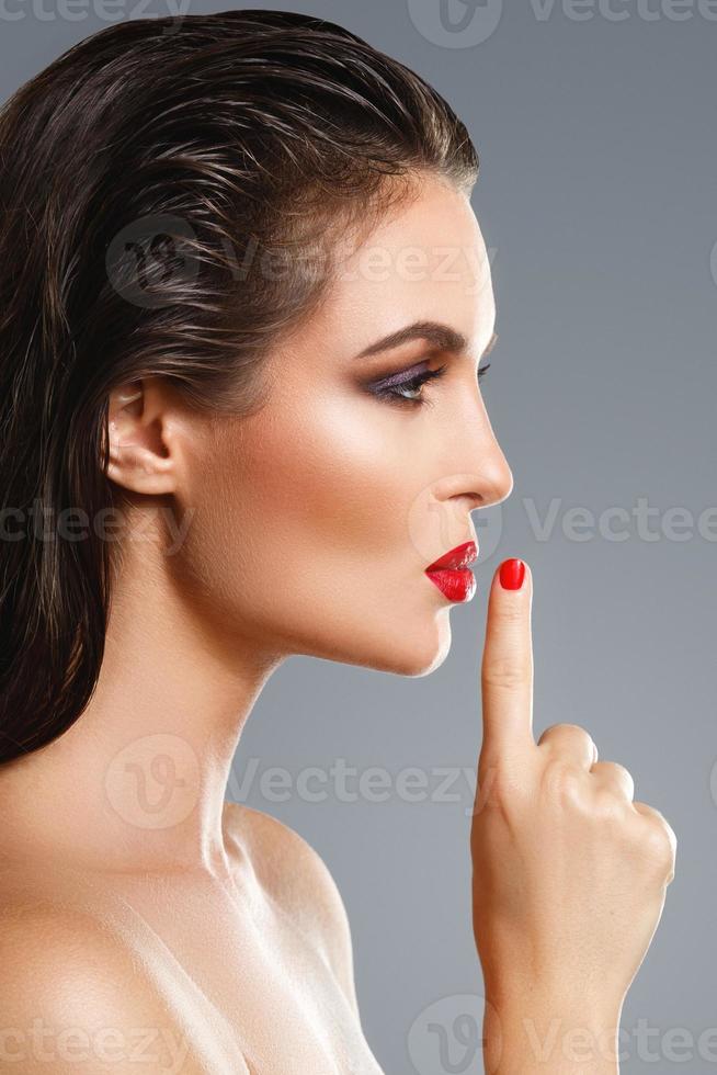 Porträt einer schönen jungen Frau mit rotem Lippenstift und Nagellack foto