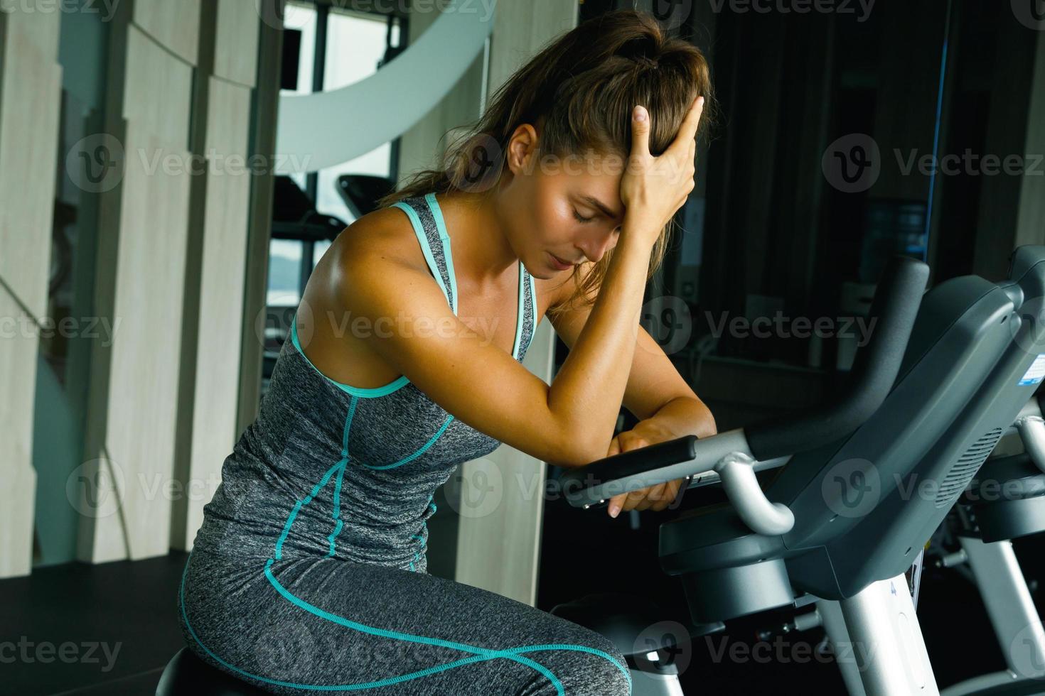 Frau im Fitnessstudio mit Übertrainingssymptomen foto