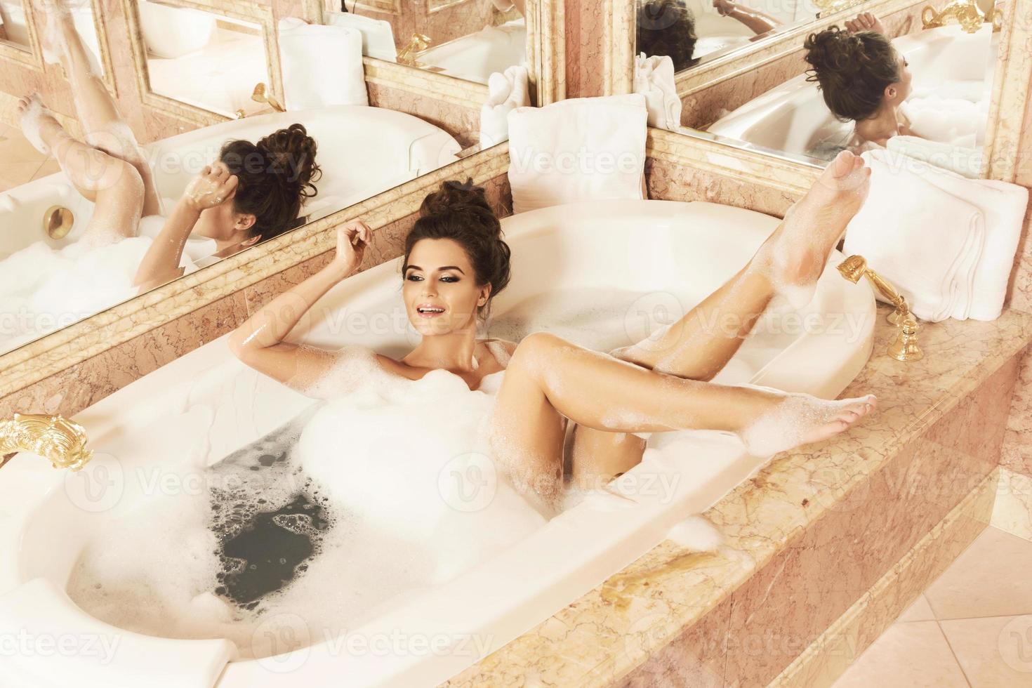 glückliche und schöne Frau nimmt ein Bad mit Schaum foto