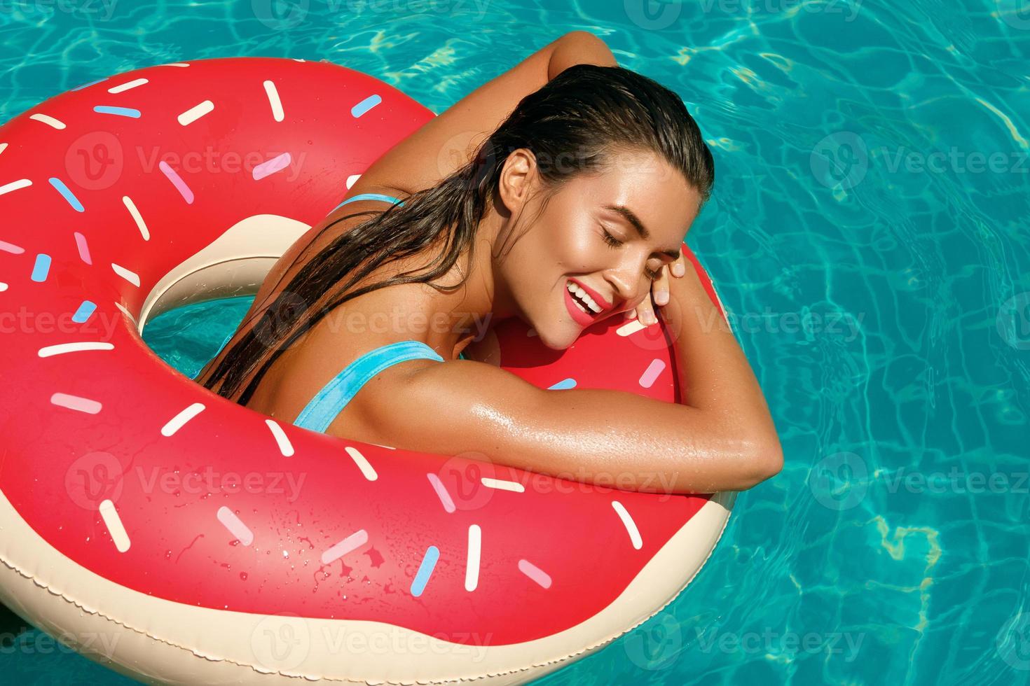 schöne Frau und aufblasbarer Schwimmring in Form eines Donuts foto