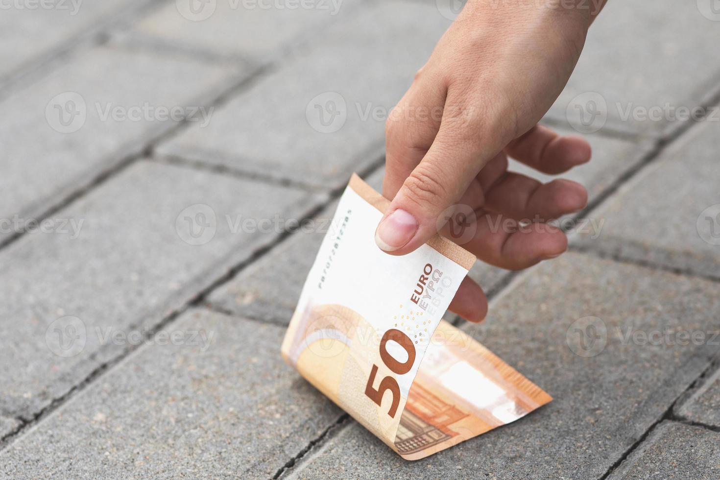 Frau pflückt 50-Euro-Banknoten vom Boden. foto