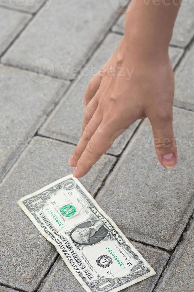 Frau pflückt eine Dollar-Banknote vom Boden. foto