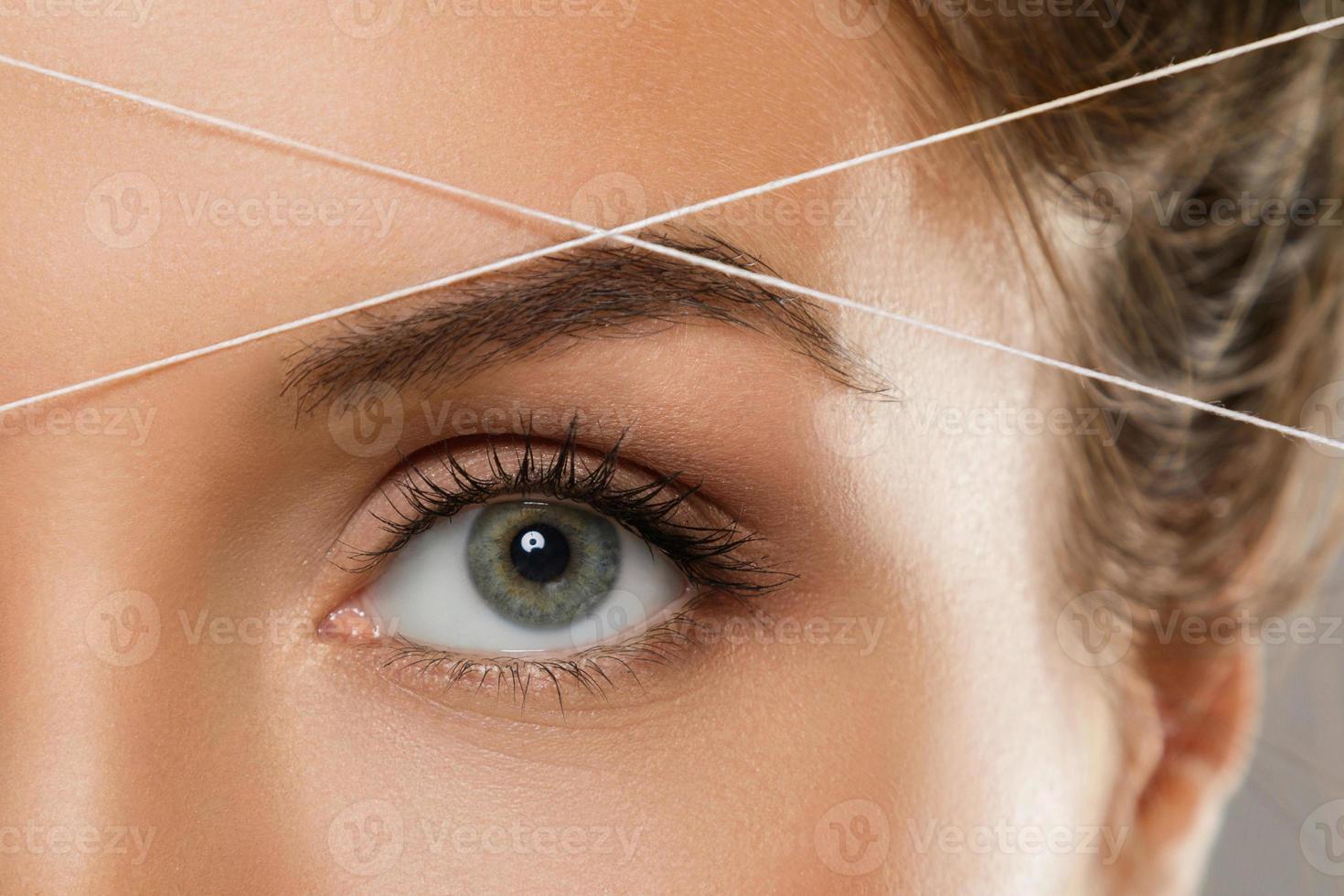 Einfädeln der Augenbrauen - Epilationsverfahren zur Korrektur der Augenbrauenform foto