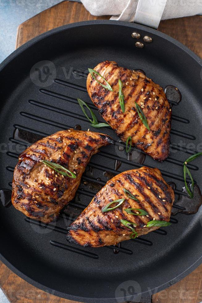 gegrillte Teriyaki-Hähnchenbrust auf einer Grillpfanne mit Frühlingszwiebeln foto