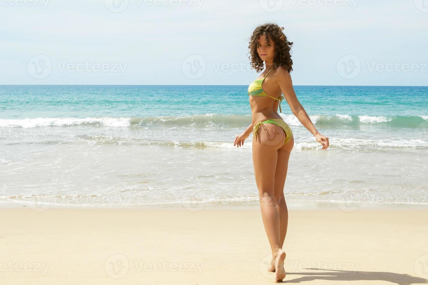 sexy Frau mit lockigem Haar am Strand foto