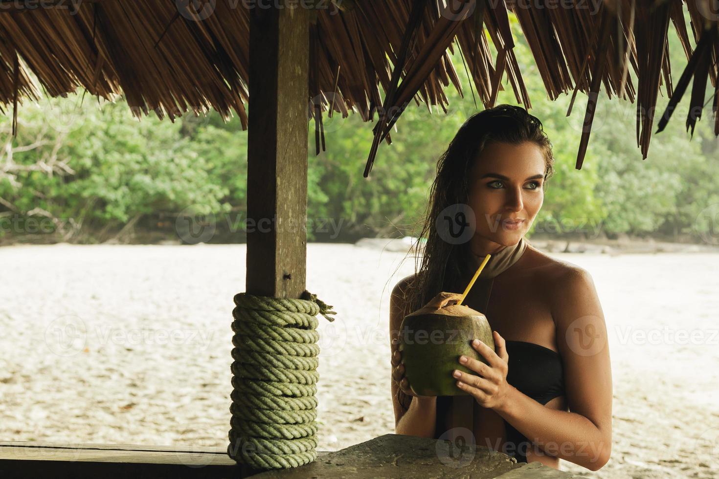 glückliche Frau genießt Kokosnussgetränk in der Strandbar foto