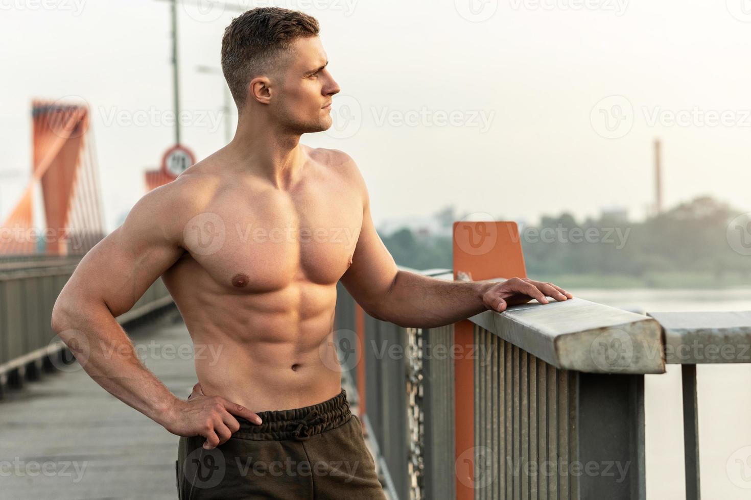 muskulöser Mann mit nacktem Oberkörper beim Fitnesstraining auf einer Brücke foto