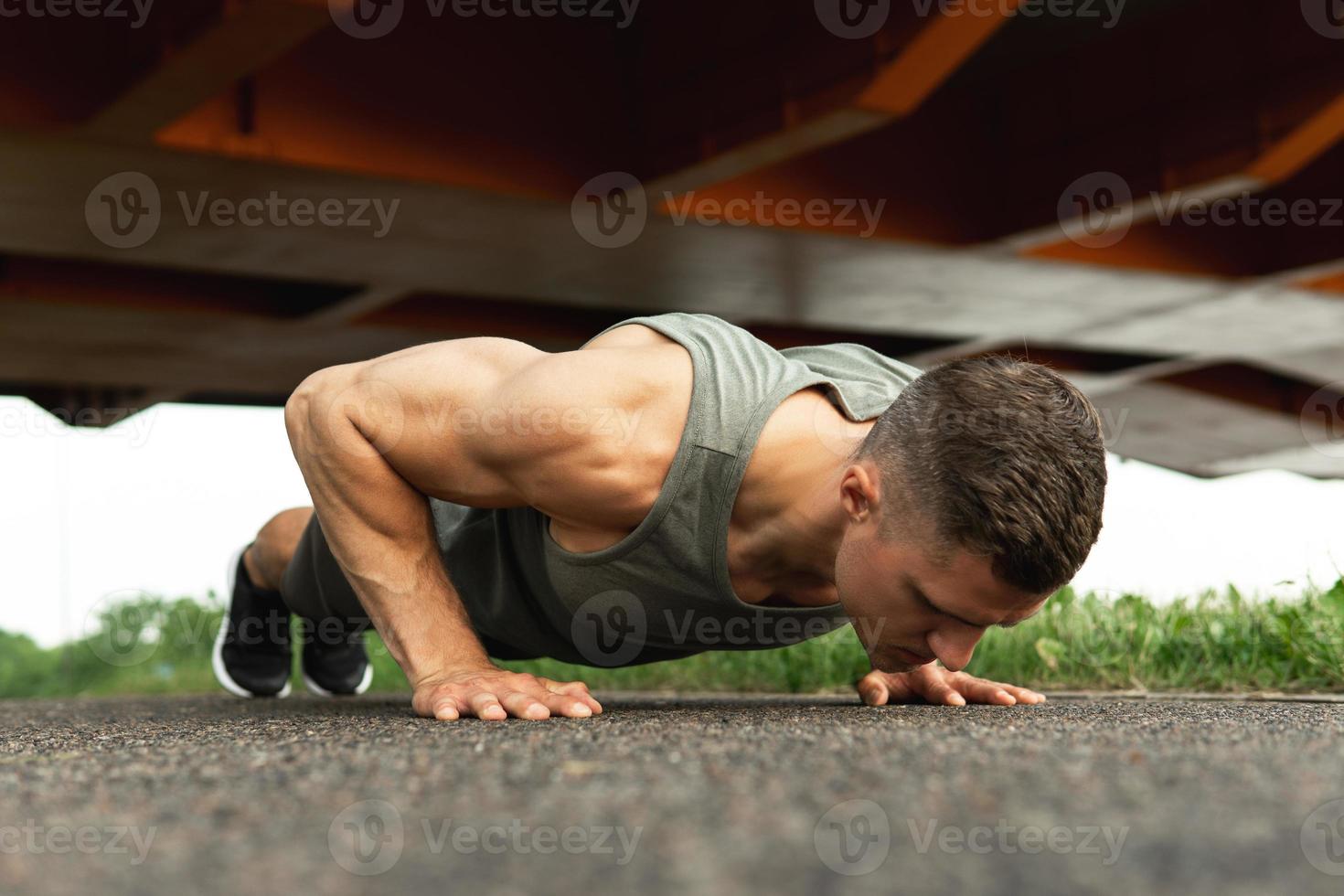 Der muskulöse Mann macht Liegestütze während des Calisthenic-Trainings auf einer Straße foto