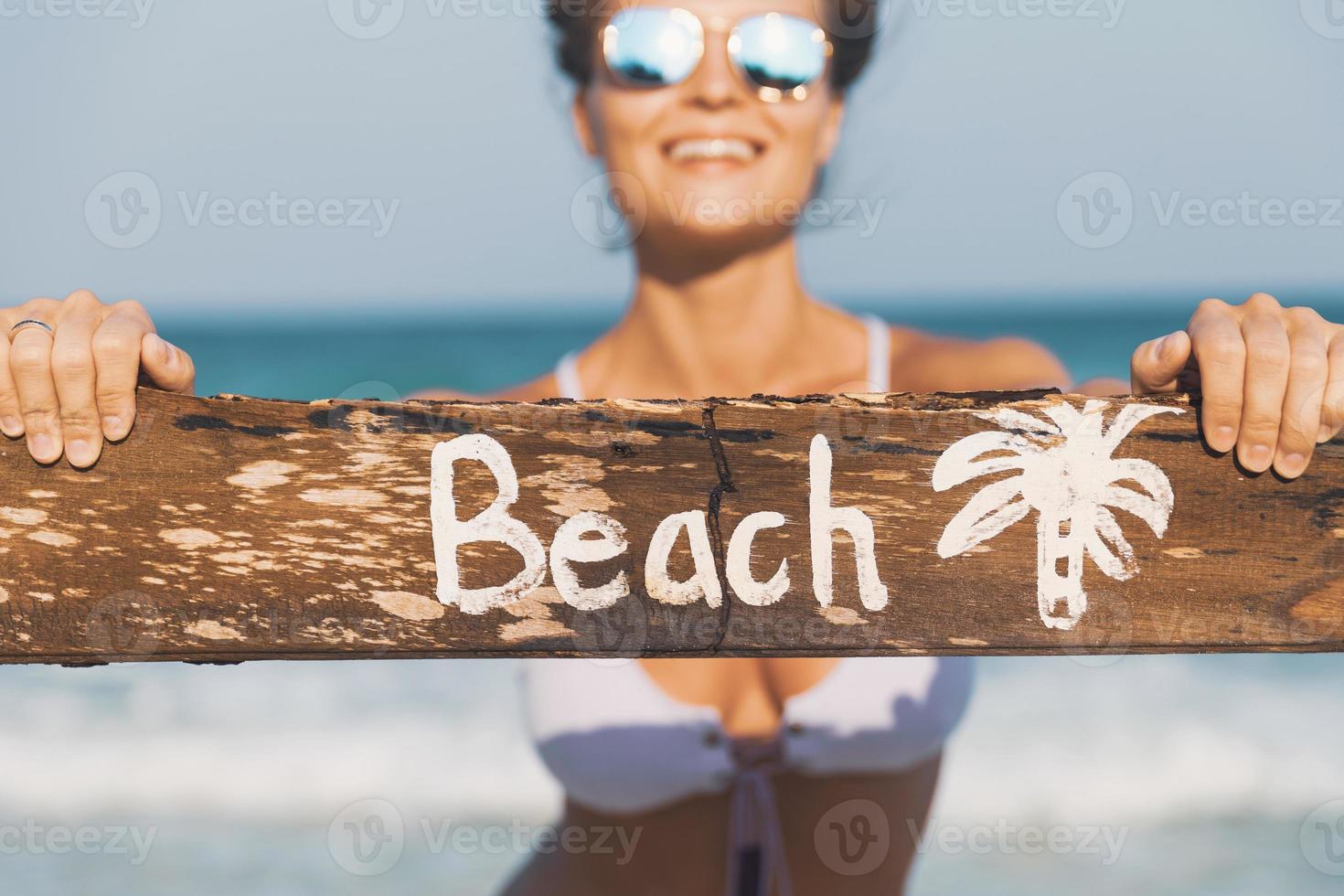 glücklicher Badeanzug mit altem Holzschild am Strand foto