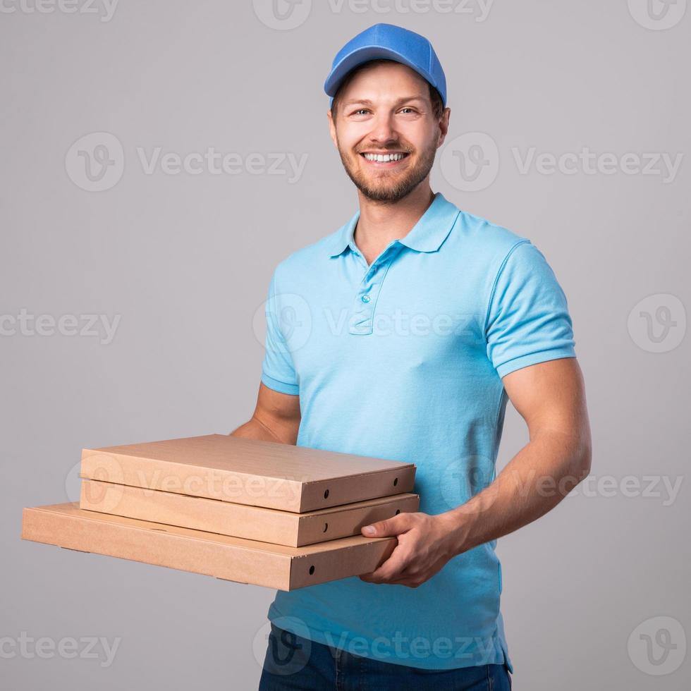 Der junge Lieferbote hält Kisten mit einer leckeren Pizza foto