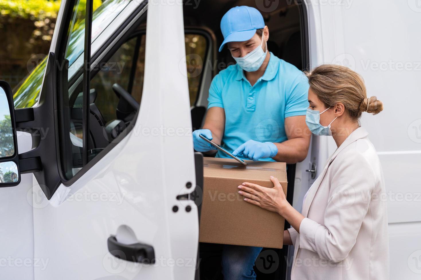 frau, die paket vom lieferanten auf einem van erhält foto