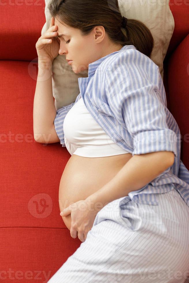 junge und schwangere frau zu hause fühlt sich krank foto