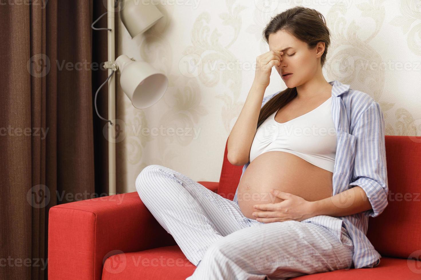 junge und schwangere frau zu hause fühlt sich krank foto