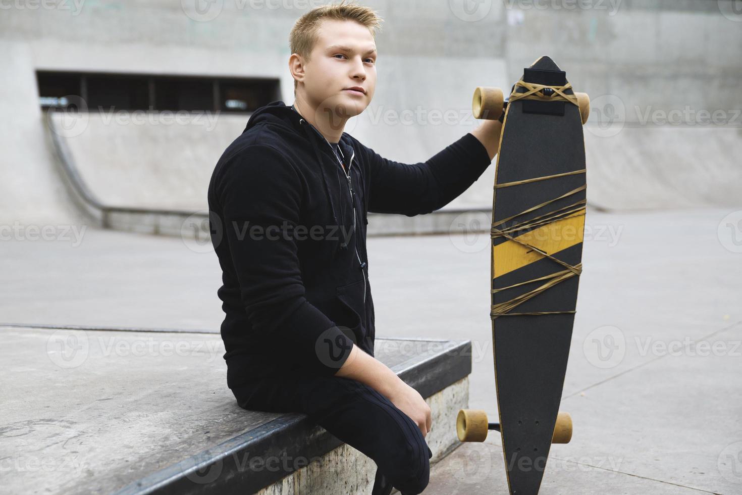 junger behinderter kerl mit einem longboard in einem skatepark foto