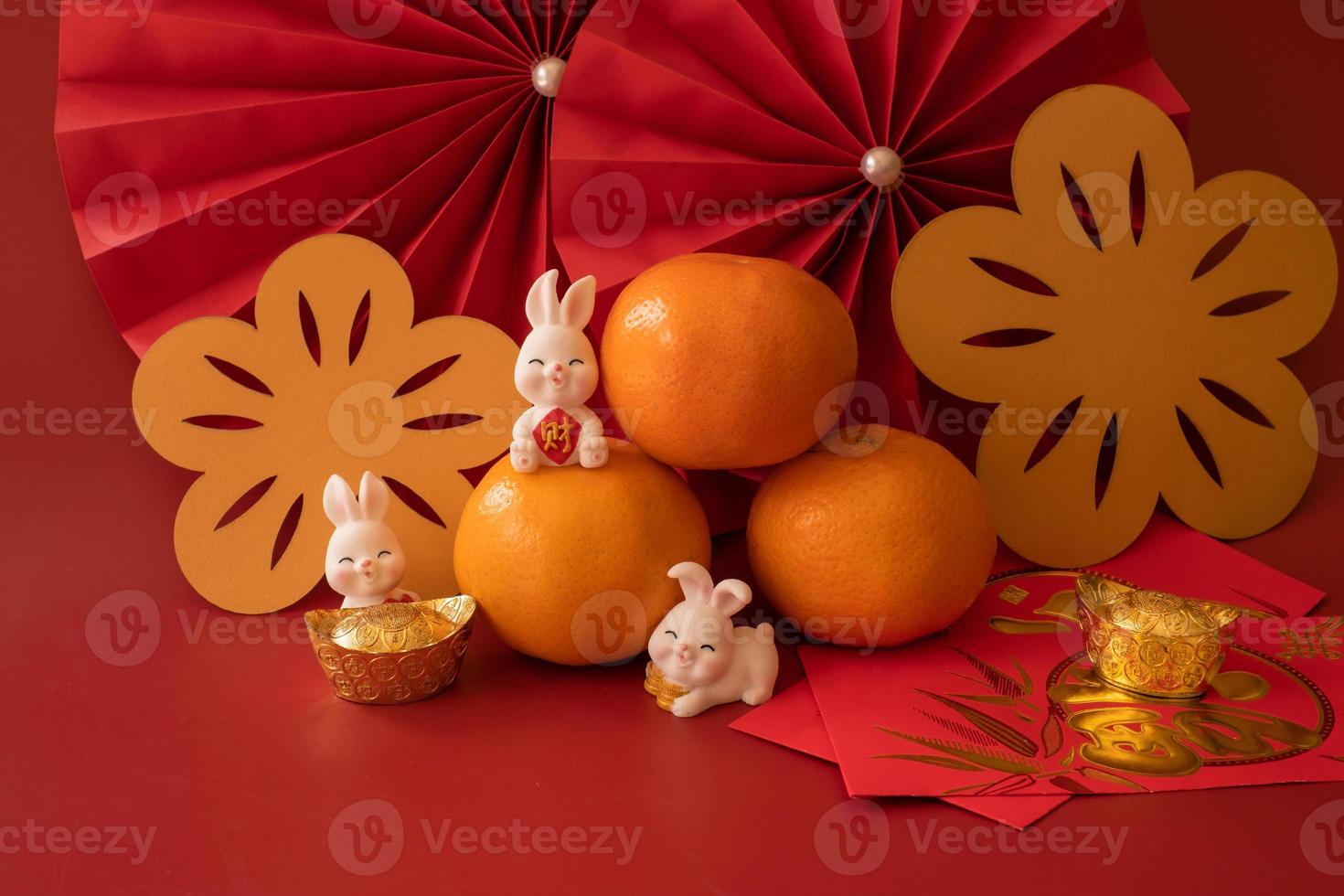 chinesisches neujahr des kaninchenfestivalkonzepts. Mandarinorange, rote Umschläge, Kaninchen und Goldbarren mit roten Papierfächern. traditionelles feiertags-mondneujahr. chinesisches schriftzeichen cai bedeutet geld. foto