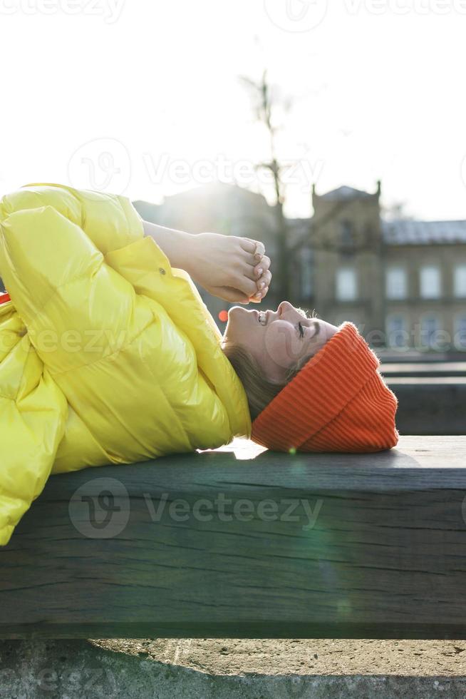 stilvolles Mädchen mit gelbem Puffer und orangefarbener Strickmütze foto