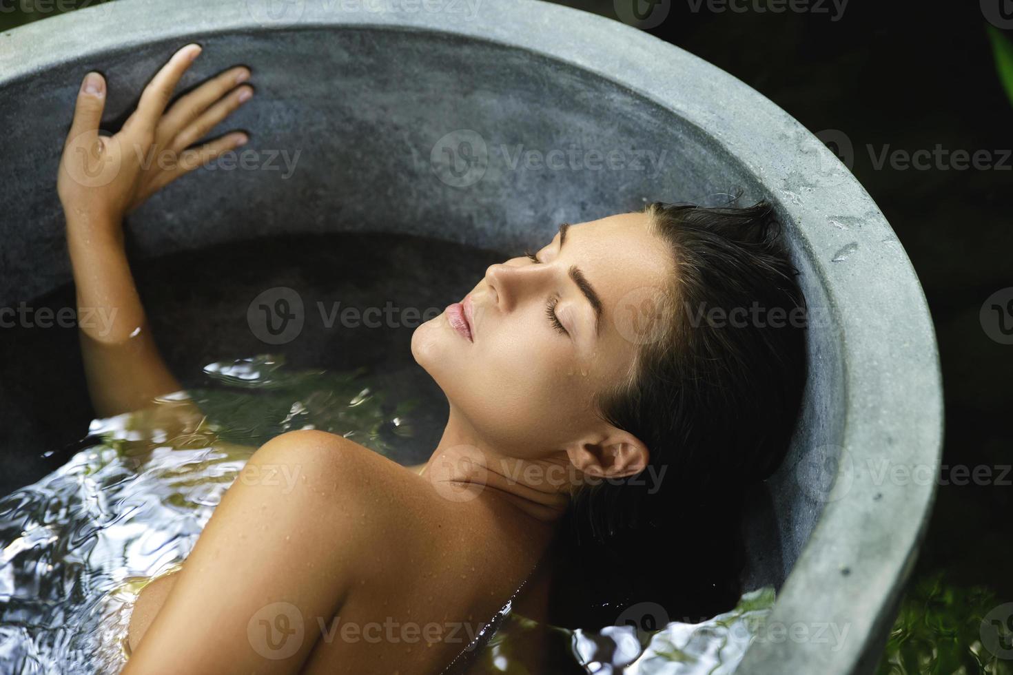 schöne frau, die in der steinbadewanne liegt und sich entspannt foto