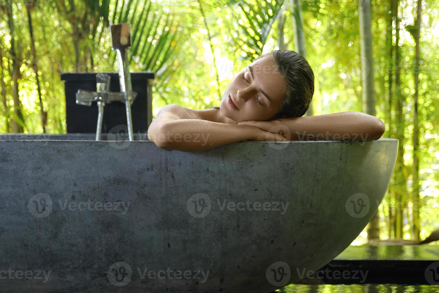 Frau, die sich in der Badewanne im Open-Air-Badezimmer entspannt foto