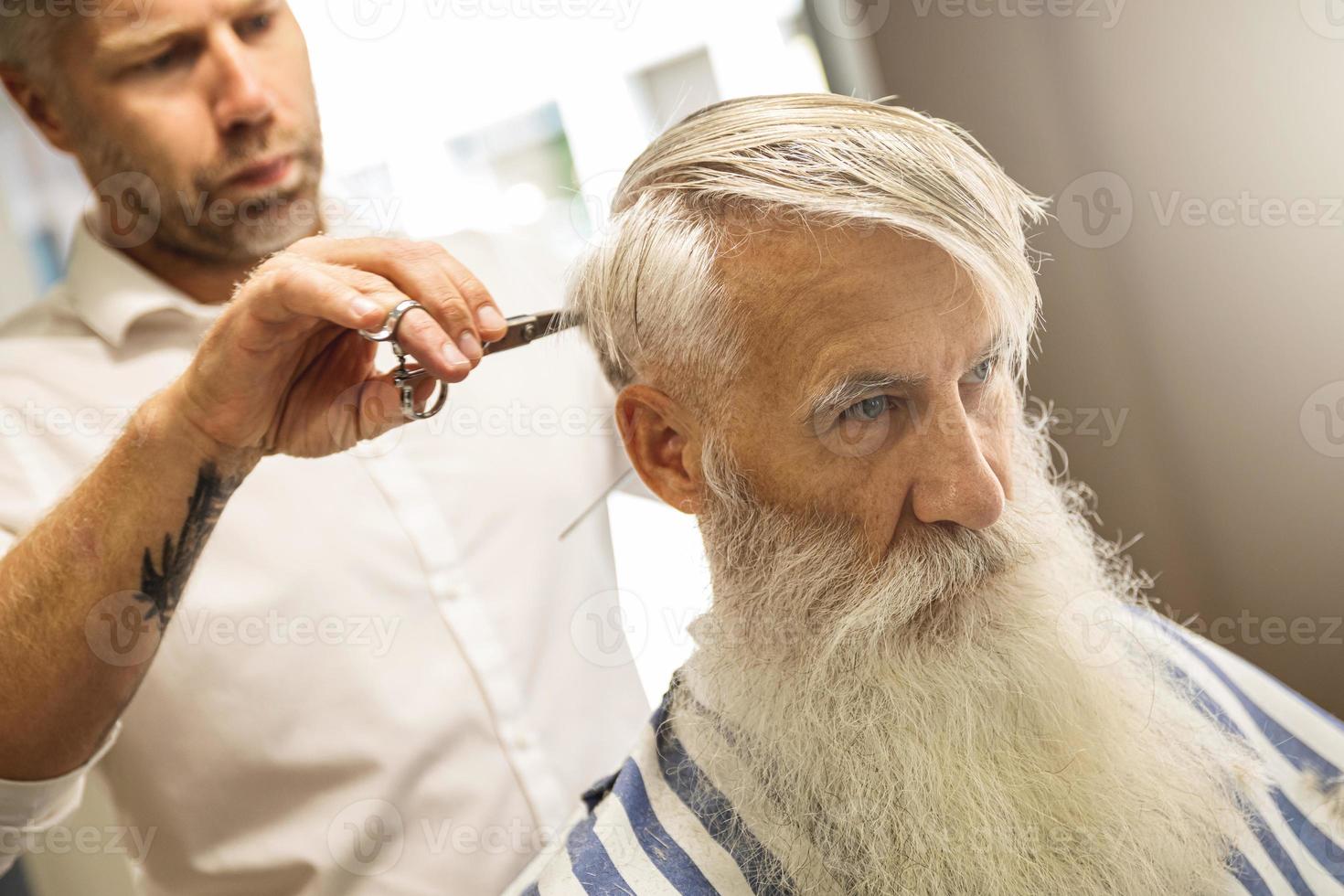 friseur, der einen stilvollen haarschnitt für einen hübschen alten mann macht foto