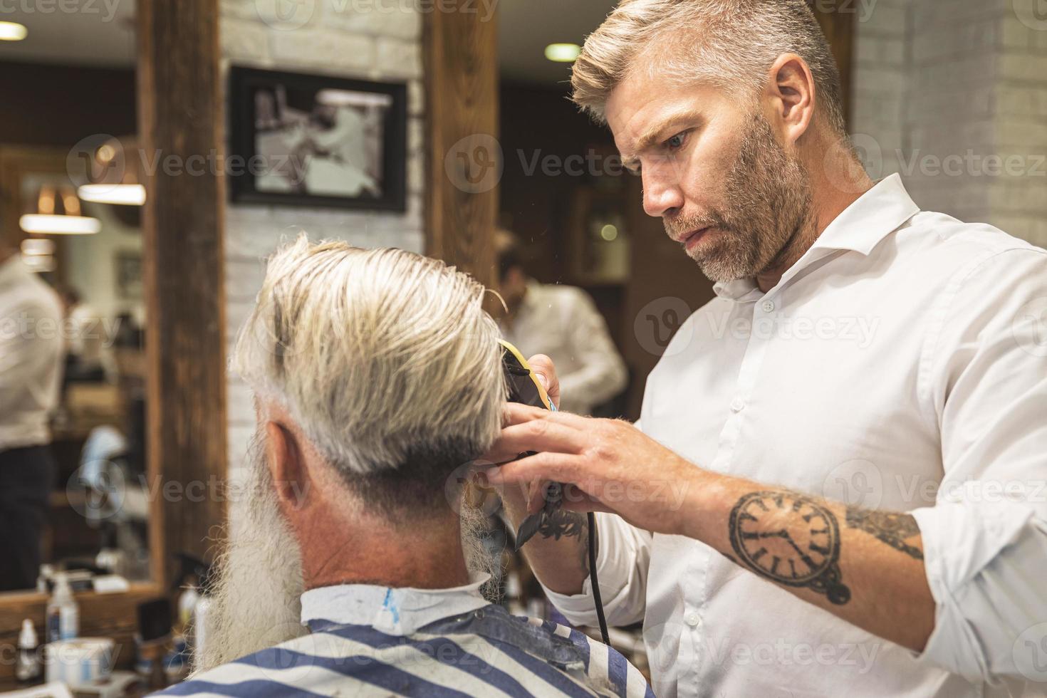 friseur, der einen stilvollen haarschnitt für einen hübschen alten mann macht foto