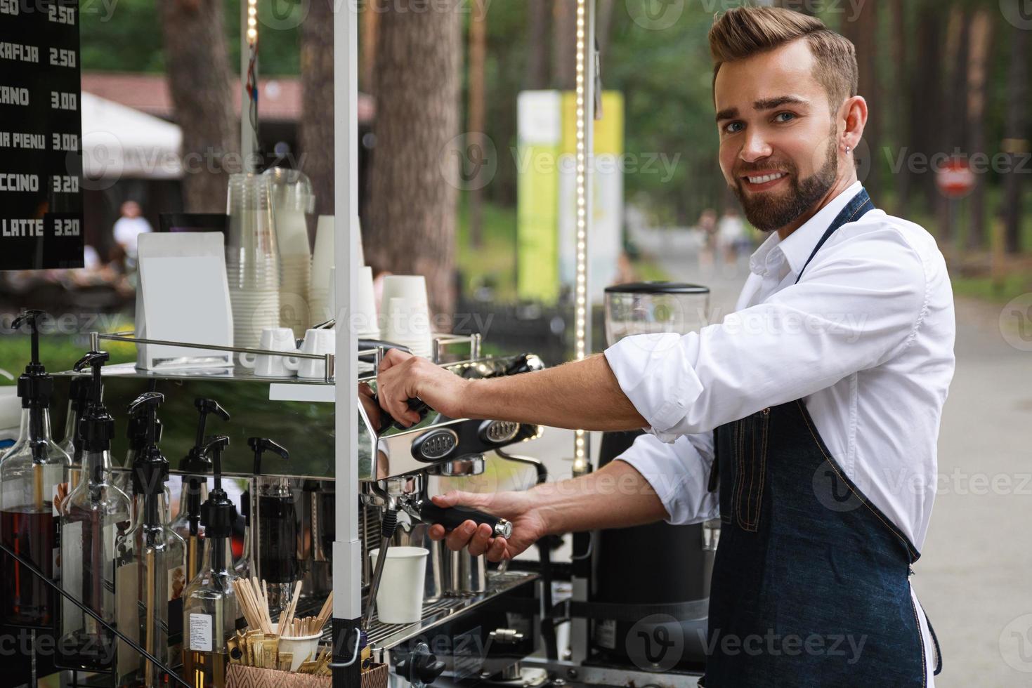 Gutaussehender Barista-Mann während der Arbeit in seinem Straßencafé foto