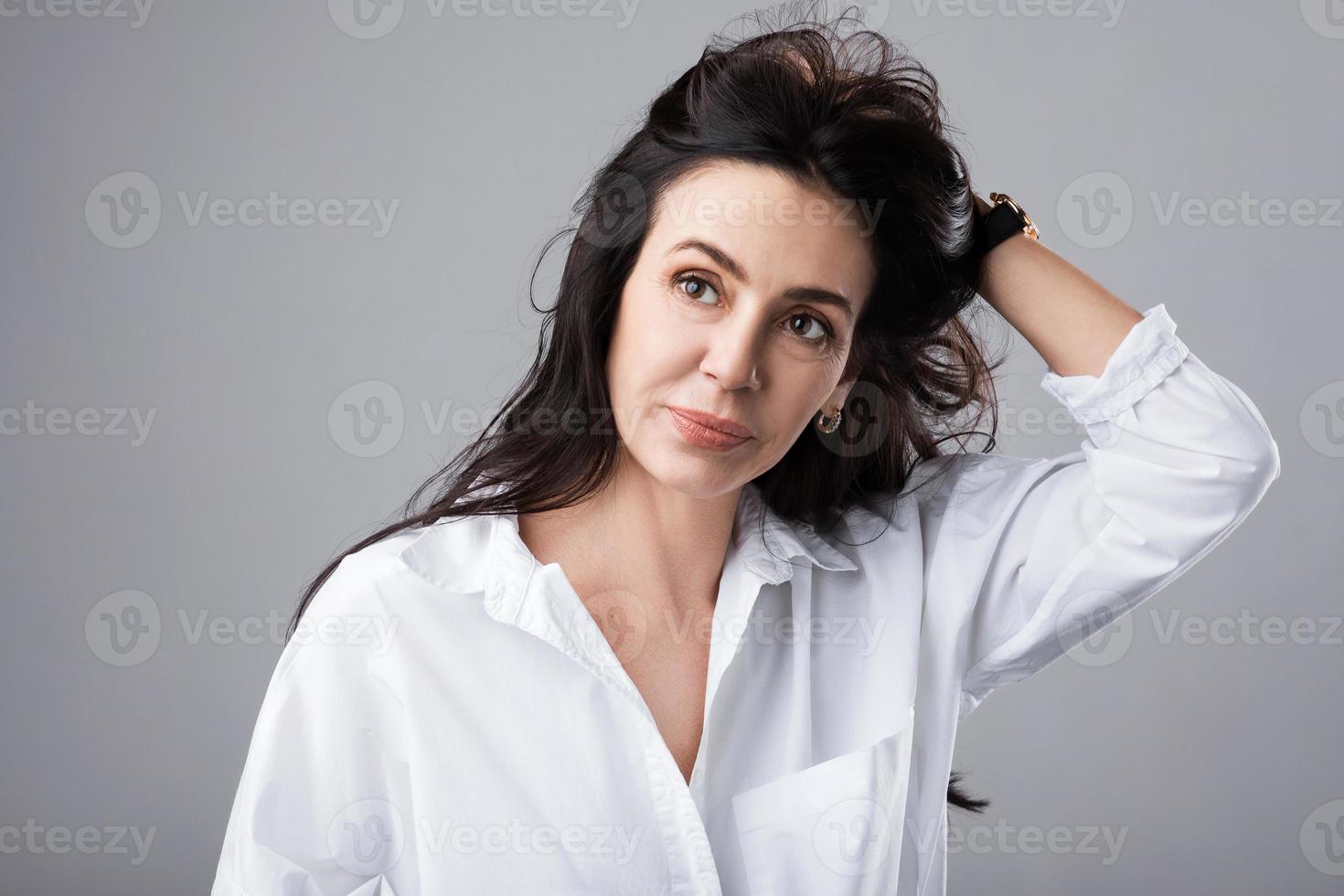 schöne Frau mittleren Alters mit weißem Hemd im Fotostudio foto