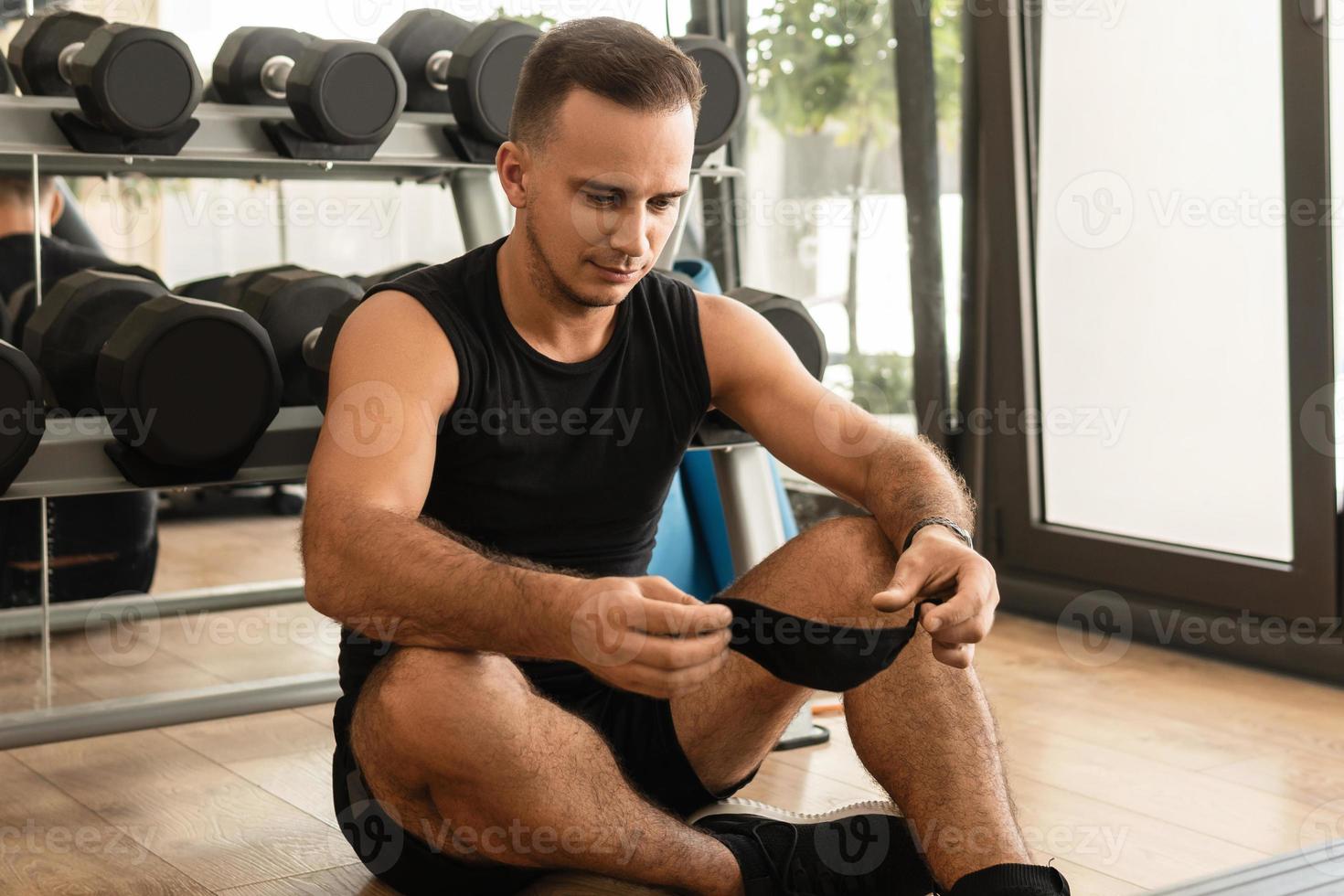 junger athletischer mann, der während seines trainings im fitnessstudio eine vorbeugende gesichtsmaske trägt foto