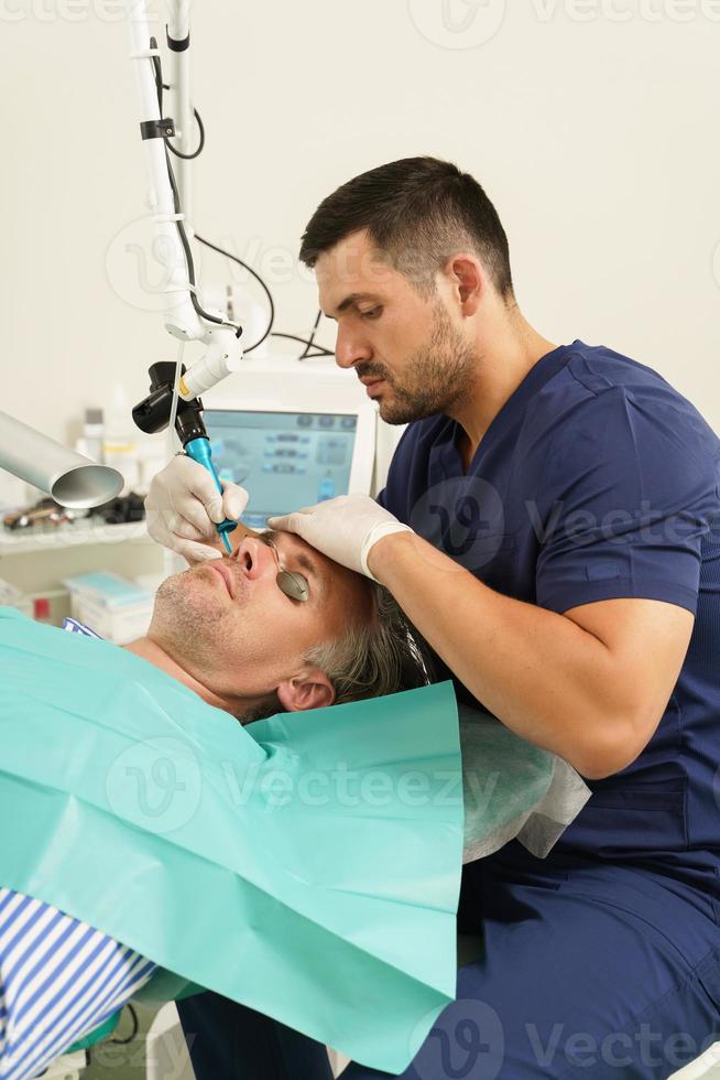 Mann mittleren Alters während der Laserbehandlung in einer medizinisch-ästhetischen Klinik foto