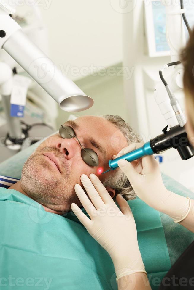 Mann mittleren Alters während der Laserbehandlung in einer medizinisch-ästhetischen Klinik foto