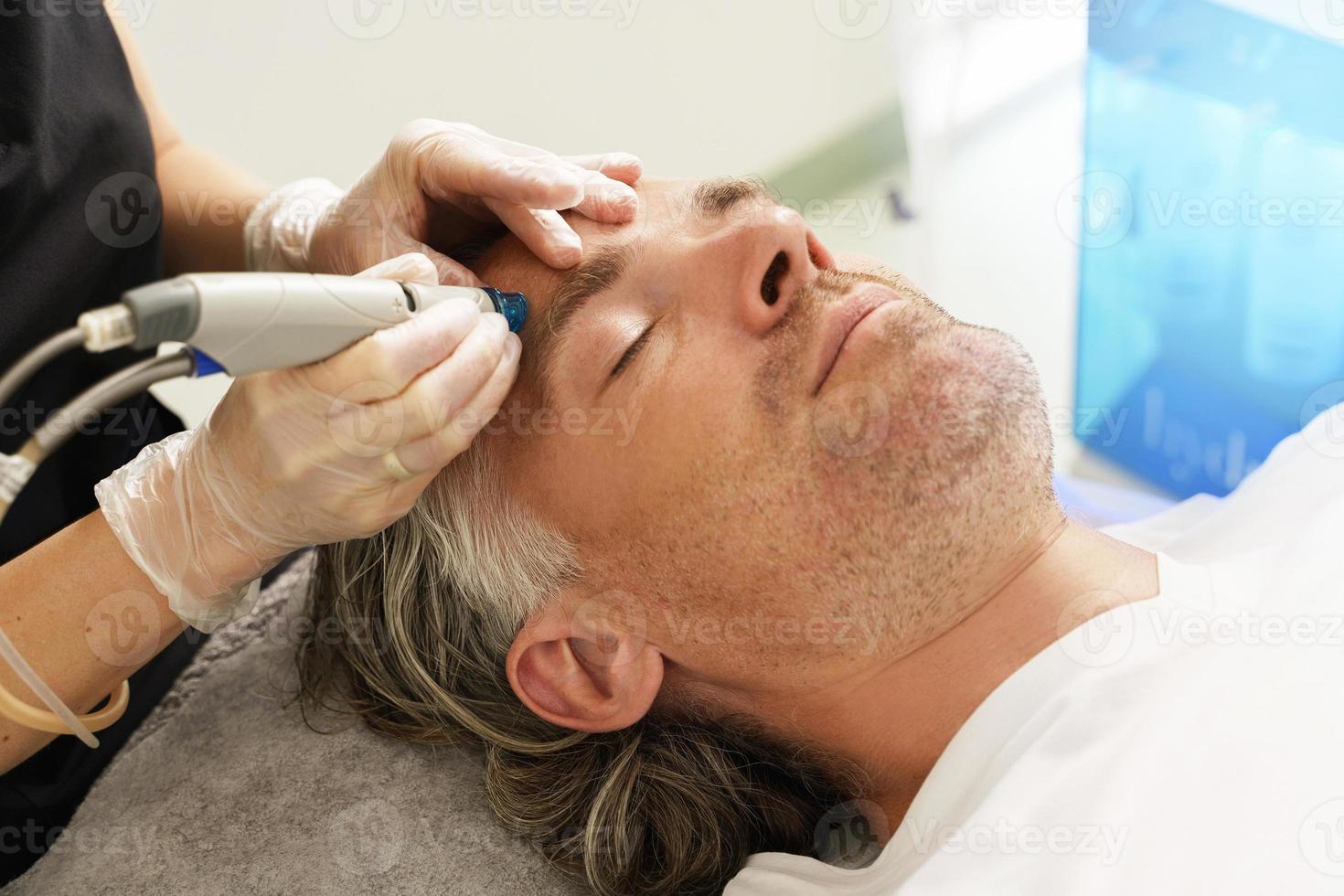 Mann mittleren Alters während der Tiefenreinigung des Gesichts in einer Kosmetikklinik foto