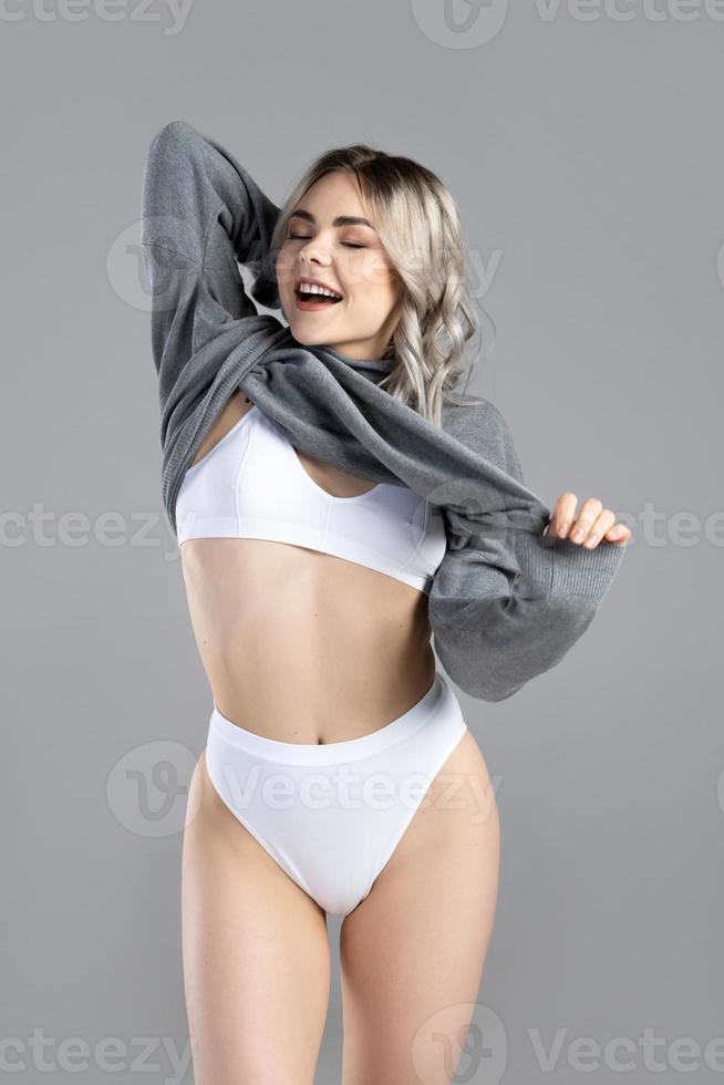 Junge und sexy Frau mit blonden Haaren mit Rollkragenpullover posiert im Studio foto