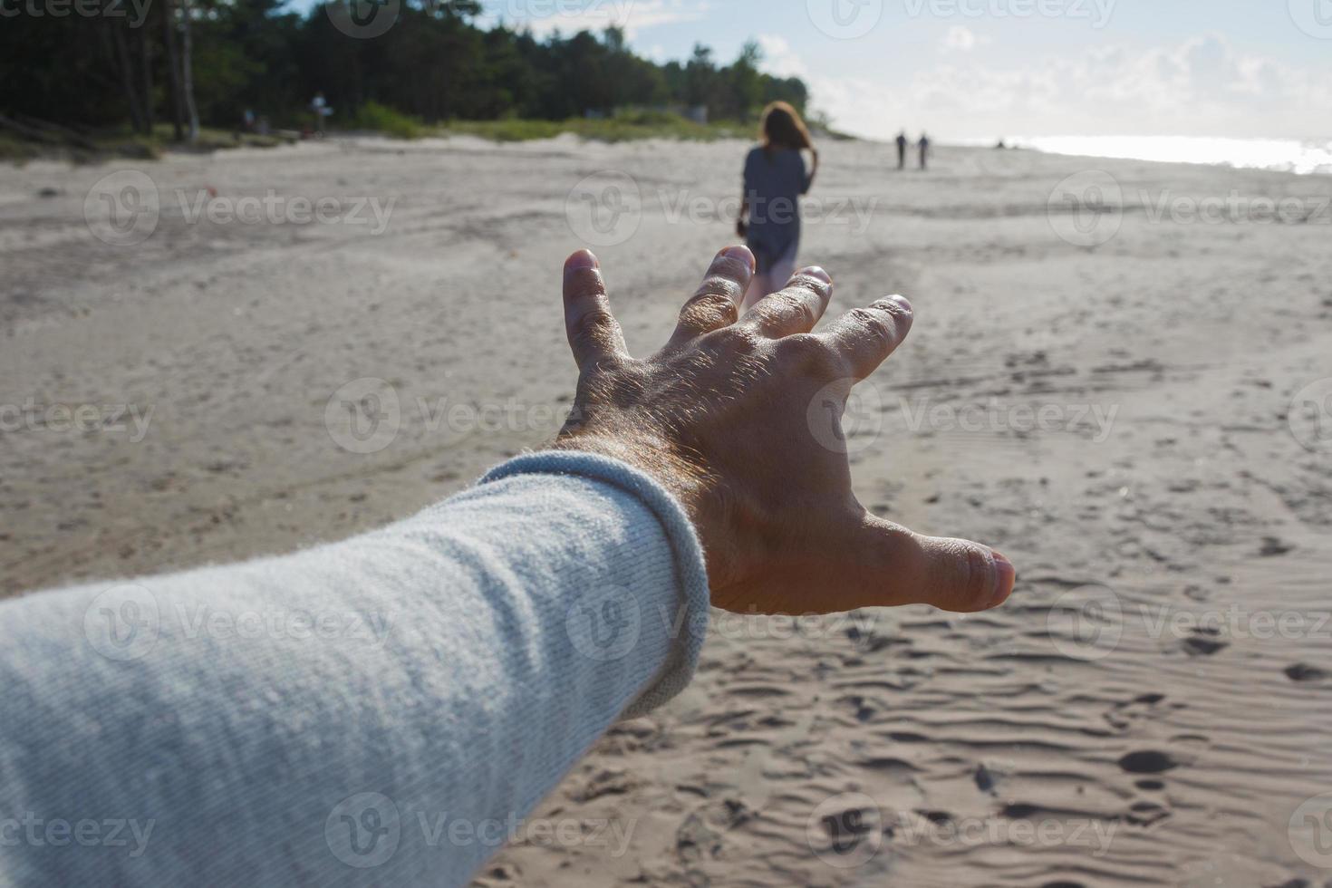 Sichtaufnahme eines Mannes, der die Hand einer Frau am Meeresufer erreicht. foto