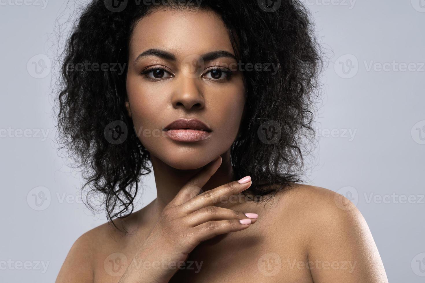schöne schwarze Frau mit glatter Haut vor grauem Hintergrund foto